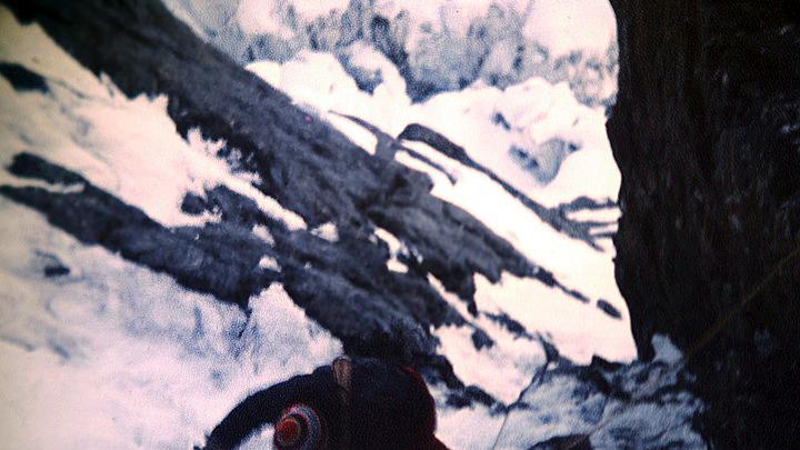 Peter Carman climbing a steep rock and ice gully above Camp One