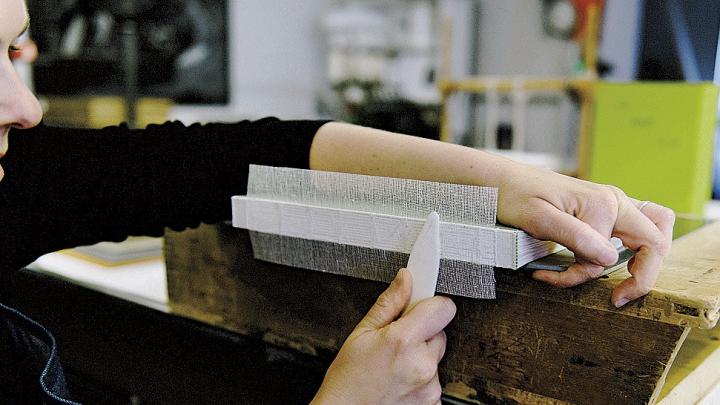 Sarah Songer applies crash (coarsely woven cloth) to strengthen a book&rsquo;s sewn spine
