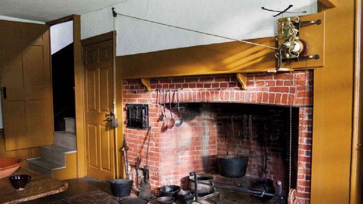 The main house kitchen, with a massive fireplace, and the narrow doorway to the service stairs.