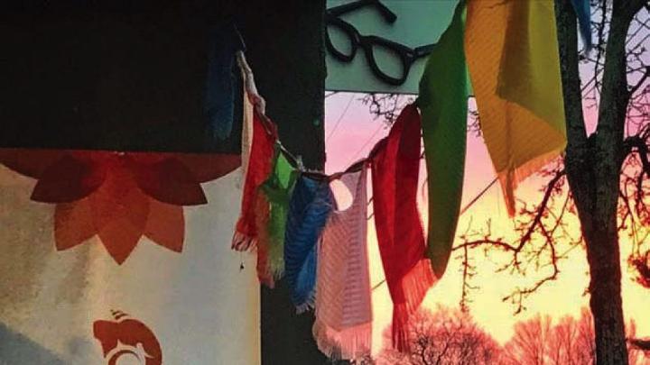 The entrance to Om Namo Yoga Studio, with prayer flags hanging high against a twilight sky.