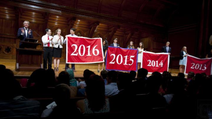 Harvard Alumni Association president Carl Muller ’73, J.D.-M.B.A. ’76 (at left), presents the Class of 2016 with its official banner during the Sanders Theatre portion of Freshman Convocation. 