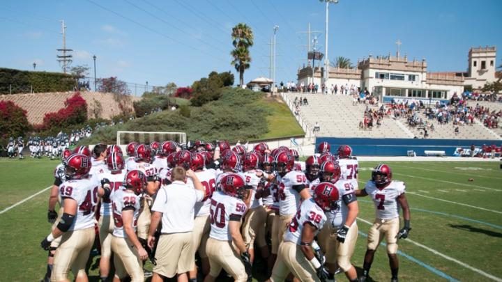 <strong>On the road:</strong> Crimson team members huddled before taking the field at Torero Stadium for Harvard’s first West Coast game since 1949. The University of San Diego’s small but picturesque facility has a seating capacity of 6,000. 