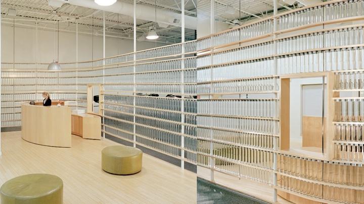 Stacks of  Voss water bottles form a translucent curving wall at a health club.