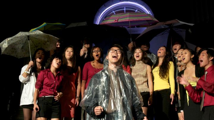 An a cappella group performs in the rain. Despite monsoon-like weather, dozens of student music and dance groups performed in Harvard Yard as part of the evening's program.