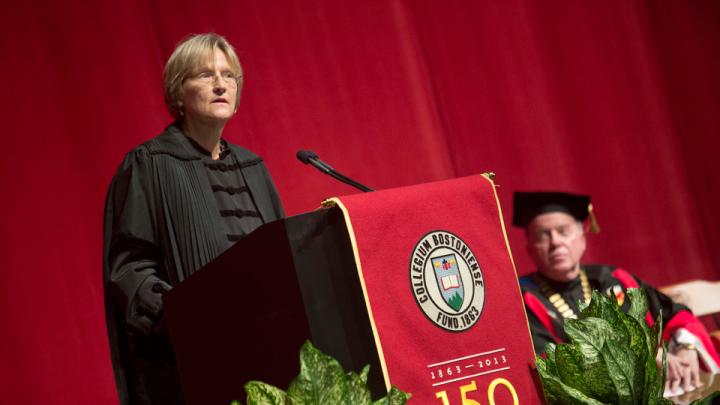 Father William Leahy, Boston College president, looks on as Drew Faust delivers her address at the Boston College sesquicentennial celebration.