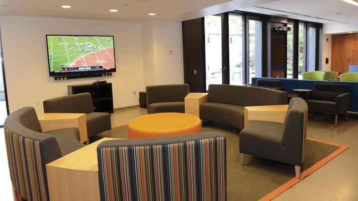 Recent renovations in Old Quincy, now renamed Stone Hall: a new community room with couches, flat-screen TV, a new kitchen, and a below-grade terrace outside the glass doors