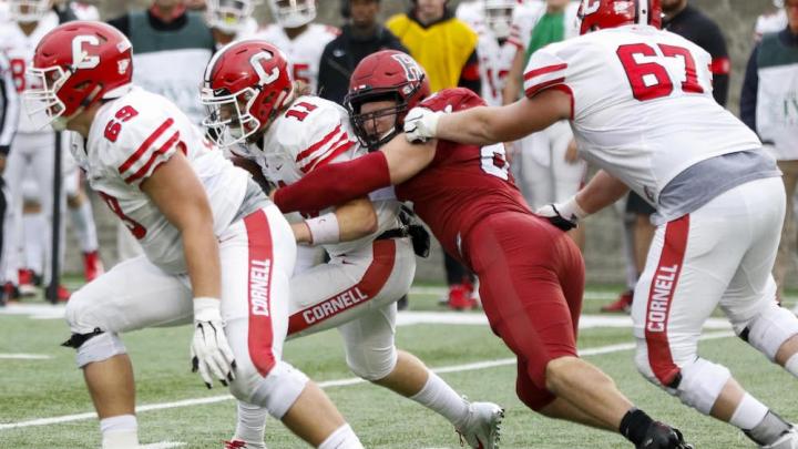 Harvard's Brogan McPartland breaks through to tackle Cornell quarterback Richie Kenney for a loss. In his first 2019 appearance, the senior defensive lineman had two of the Crimson's six sacks.