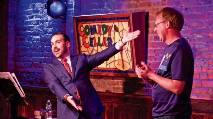 Greenbaum excitedly gesturing toward an audience member on stage at the Comedy Cellar