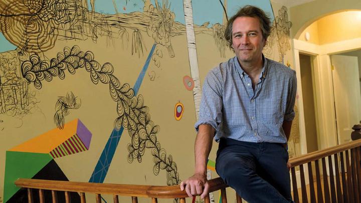 Dan Chiasson at home in front of a “sometimes delightful, sometimes disturbing” mural by David Teng Olsen, which appears in The Math Campers.