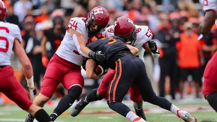 Two Harvard linebackers tackle a Princeton receiver
