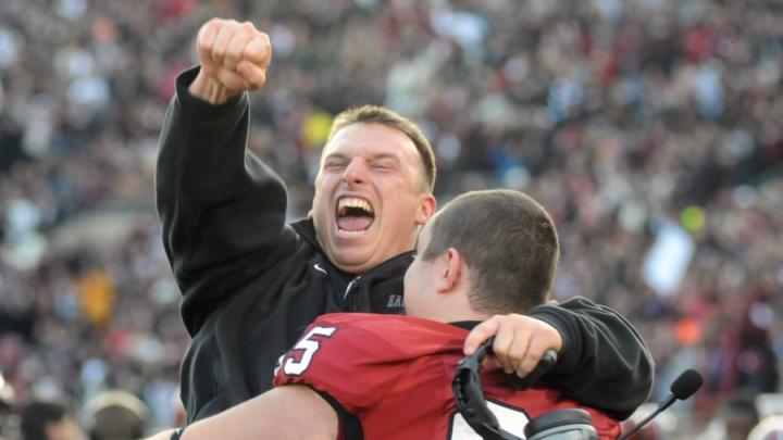 Defensive line coach Michael Horan and reserve tackle Adam Riegel ’13 share a jubilant hug after a 34-24 victory in The Game.