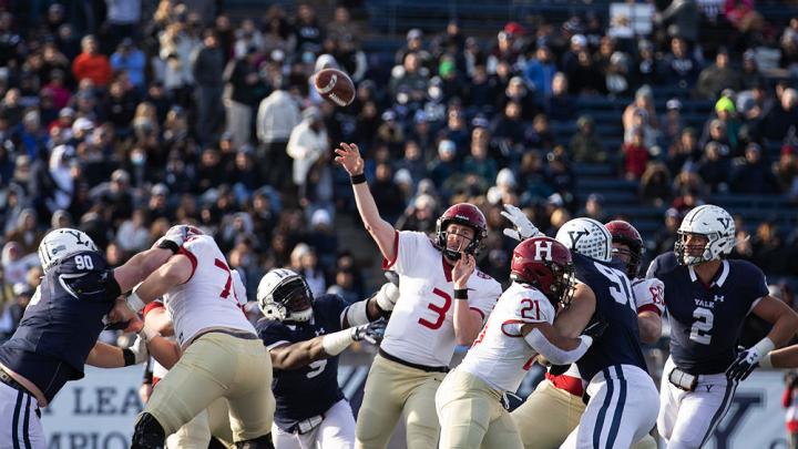 Luke Emge throws the football amidst Yale defenderss