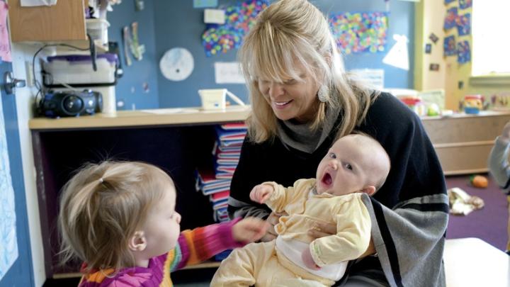 Mary Kinsella Scannell, vice president for early education and care, plays with baby Kinsey Ferraguto and toddler Margot Vorhees.