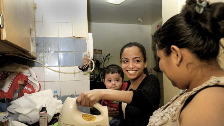 Katty Morocho (center), a social worker for Little Sisters, teaches client Zenaida Vega to bake a cake while Vega’s nephew, Miguel, looks on. Vega hopes to find work at a bakery.