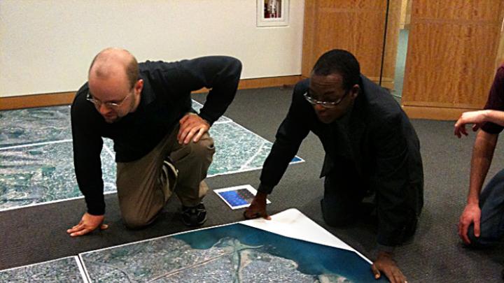 At the Center for Geographic Analysis office, the Harvard-MIT Data Center's Eric Alderman examines a map of Port-au-Prince with Jean-Lucien Ligonde, a businessman in the Boston Haitian community, in preparation for sending the map to Haiti to be used in relief work.