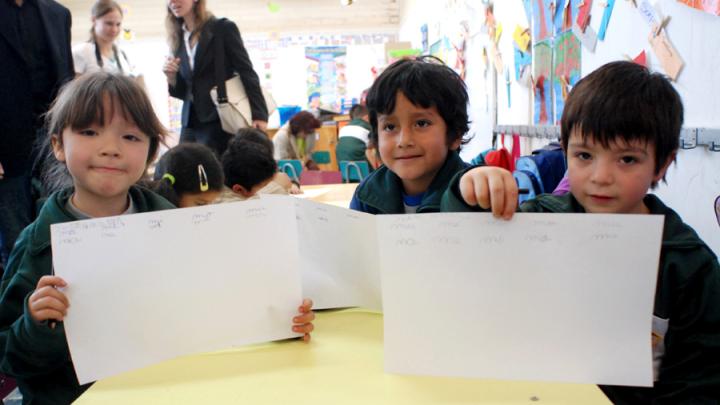 Children in a UBC classroom display a writing exercise on which they've been working. 