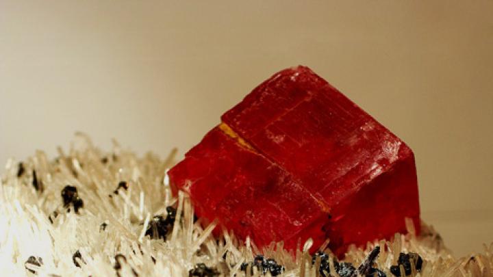 A rhodochrosite rhombohedron on quartz, with brown flecks of hübnerite in the foreground, from the Sweet Home Mine in Alma, Park County, Colorado. Each edge of the rhombohedron is about two inches long. 