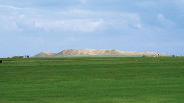 The high central mound of Tell Brak, formed by generations of mud structures built on top of one another, rises out of the alluvial plain.