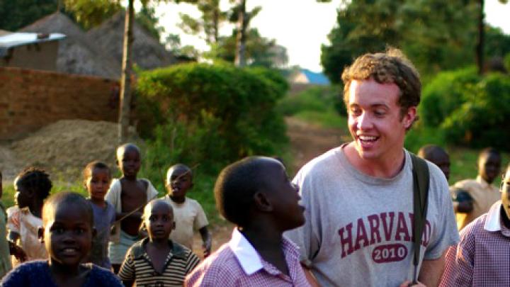Christopher Higgins ’10 walks through Busia, Uganda, in July with residents of the New Hope orphanage (wearing the crimson-and-white New Hope school uniform) and children from the community.