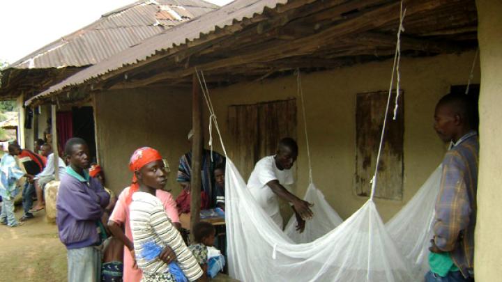 In Nganyahun village, a Red Cross volunteer and a community leader who work with GMin teach residents how to put up bed nets.