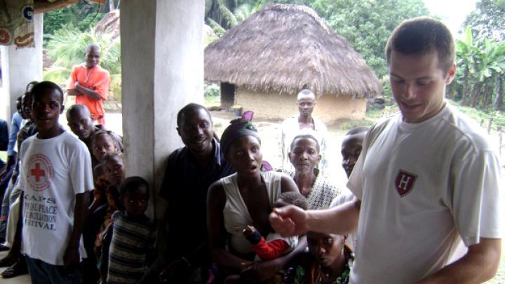 Using notes to bolster his command of Mende, the local language, Sam Slaughter ’09 introduces himself and the GMin team to villagers.