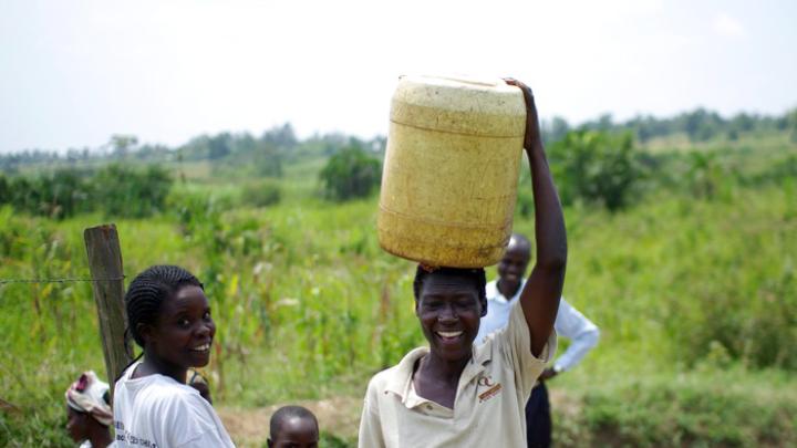 Loice Pamba (right) heads home with her (purified) water, while Everlyne Narocho—the resident responsible for making sure the dispenser stays filled at this site—looks on.