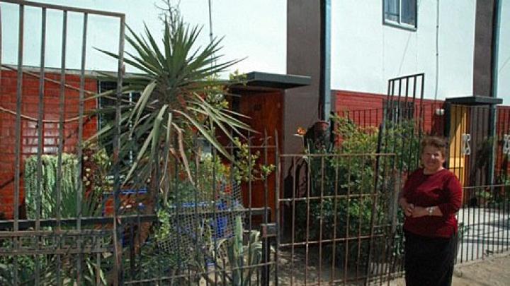 Ortega stands in front of her home. She fenced in her yard and filled it with plants, which she sells to support herself and her two-year-old grandson.