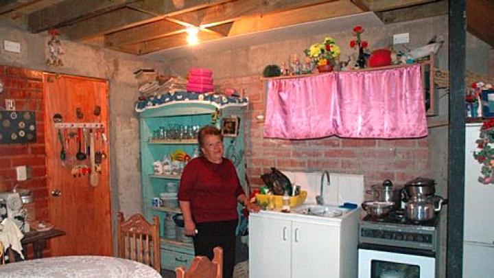 Rosa Estrella Ortega Roa stands in the kitchen of her home in the ELEMENTAL development in Santiago's Renca neighborhood. She moved in just a few months ago, and plans to finish the walls and ceiling. Ortega says even with unfinished walls and plywood overhead, this is a big improvement over her former home in the campamento, which had a muddy dirt floor.