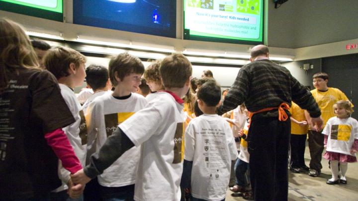 Cocoa powder and cocoa butter don’t mix well on their own, so an emulsifier such as soy lecithin is a necessary ingredient for smooth-textured chocolate. Here, volunteers illustrate this process as each emulsifier molecule (those in white T-shirts) holds hands with one cocoa-powder molecule (in brown T-shirts) and one cocoa-butter molecule (in yellow T-shirts). 