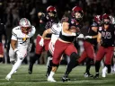 Harvard Football player 29 runs with football with Brown players running after along with other Harvard players