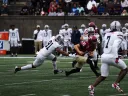 Harvard football player runs with ball as Howard players try to stop him