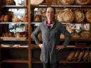 Apollonia Poilâne standing in front of rows of fresh-baked loaves at her family's flagship bakery