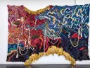 Large tapestry featuring colorful woven saris and metal bells 