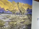 mural of dinosaurs and boy touching a fossil