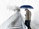 A man carrying an umbrella walks beside a set of train tracks