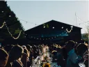 People gathered at a long, outdoor dining table set with wine glasses, candles, and flowers. 