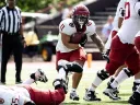 Harvard player 11 runs with the ball with other Harvard players fending off Brown players