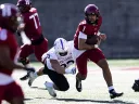 Holy Cross player attempts to tackle Harvard player 1 who is running with ball