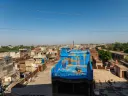view of rooftop buildings and a colorful roof painted blue and gold as an art display