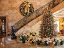 Marble House foyer decorated with a Christmas tree, poinsettias, and a large wreath on the staircase.