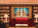 Library looking room with bookcases and a red sofa and accent chairs 