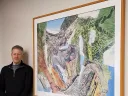 Darren Sears stands to the left of his framed work "Summit"