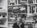 Edwin Frank sits with stacks of books in the background
