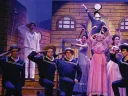 Theatrical performance of H.M.S. Pinafore with actors in sailor costumes and a pink dress.