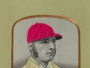 Portrait of Tom Cannon in a striped jockey uniform and matching cap.