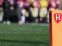 orange post on a football field with the Harvard Athletics shield