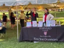 people stand at a table that reads "Harvard College Dean of Students Office First-Year Orientation"