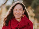 A smiling woman in a red scarf with brown hair