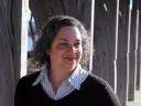 Catherine Zipf smiling, wearing striped shirt and dark sweater outdoors.