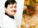 A chef smiling, dressed in a white coat, next to a close-up of a dish garnished with herbs.